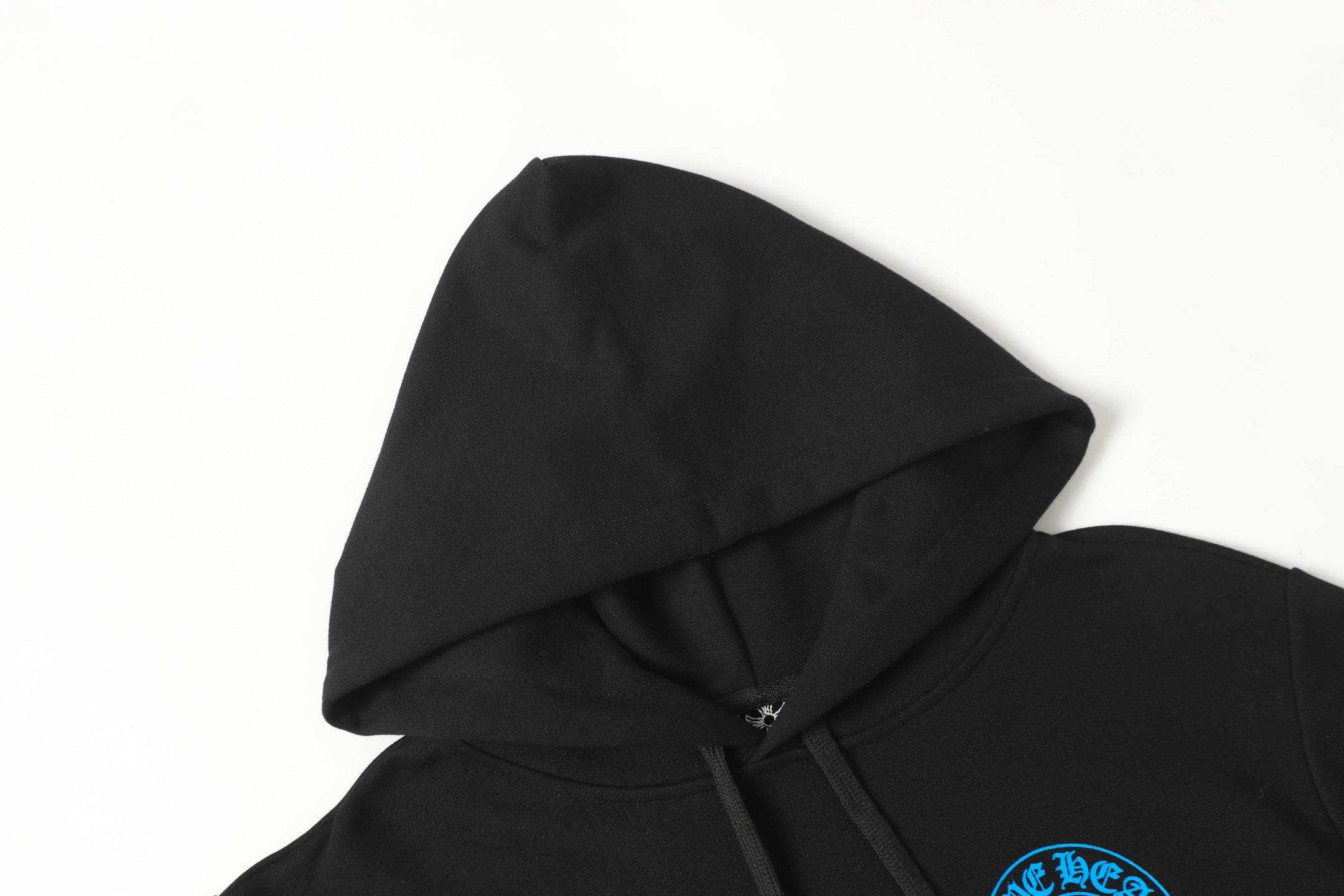Black hoodie hood and neckline close-up with drawcords and partial blue emblem