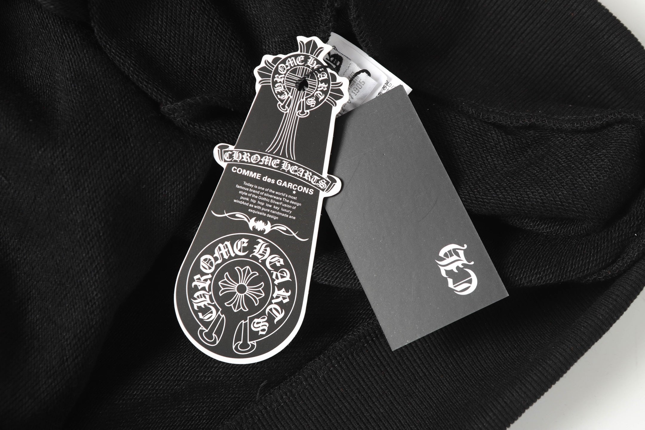 Black hoodie garment tags and neck label close-up on fabric