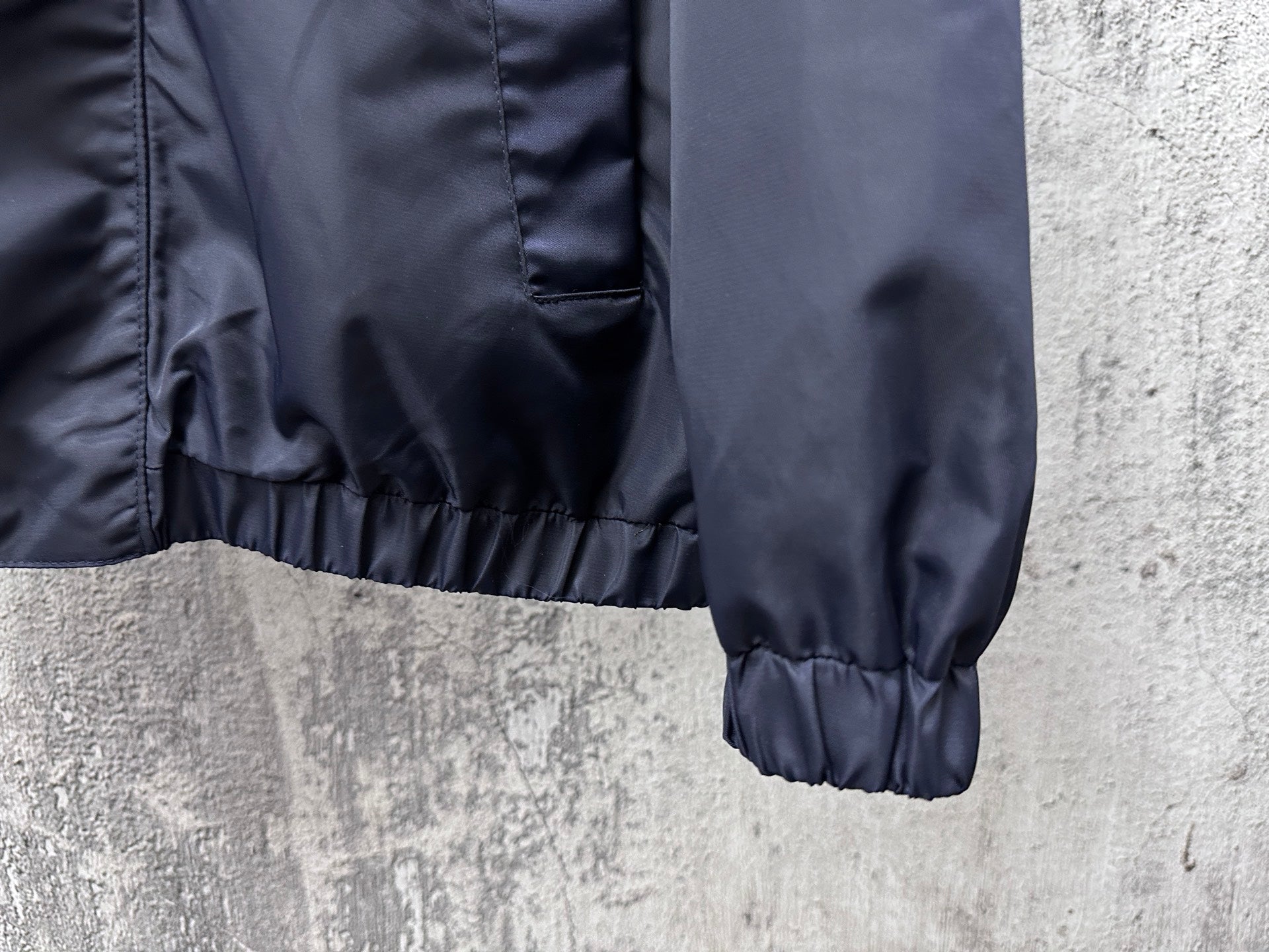Long hooded jacket hem and elastic cuff detail, dark navy blue.