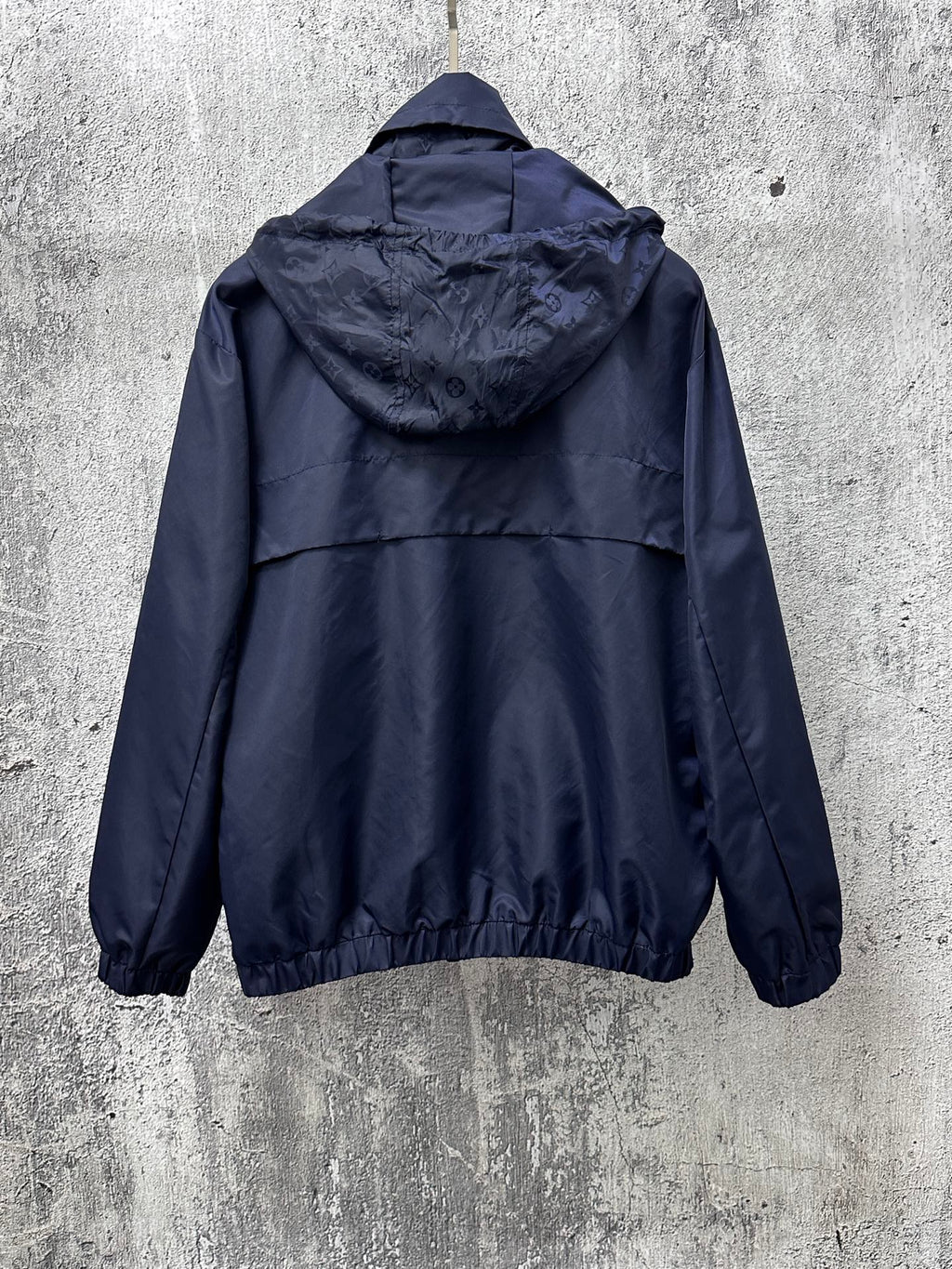 Long hooded jacket, rear view with adjustable hood and full zipper, dark navy blue.