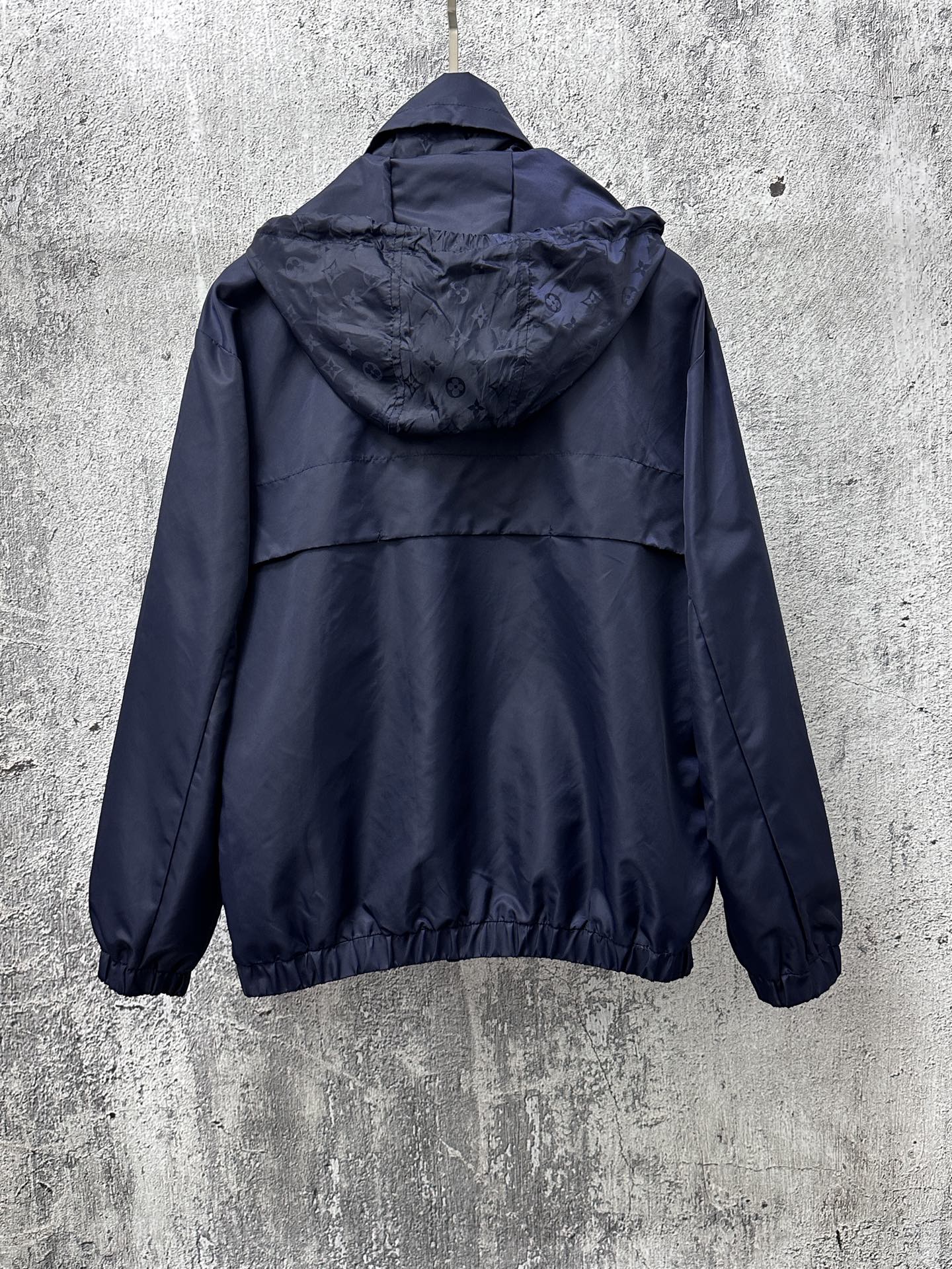 Long hooded jacket, rear view with adjustable hood and full zipper, dark navy blue.