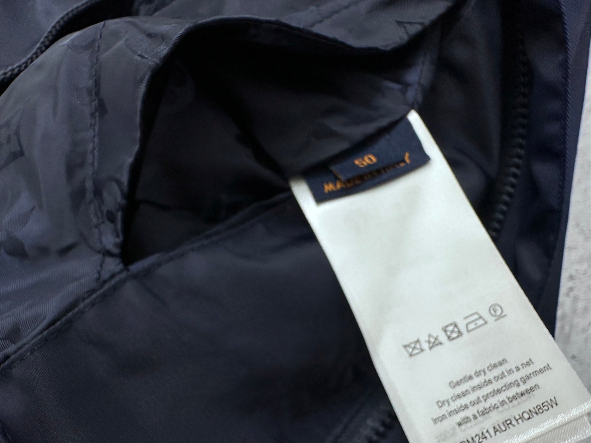 Louis Vuitton garment tag label inside long hooded jacket, dark navy fabric.