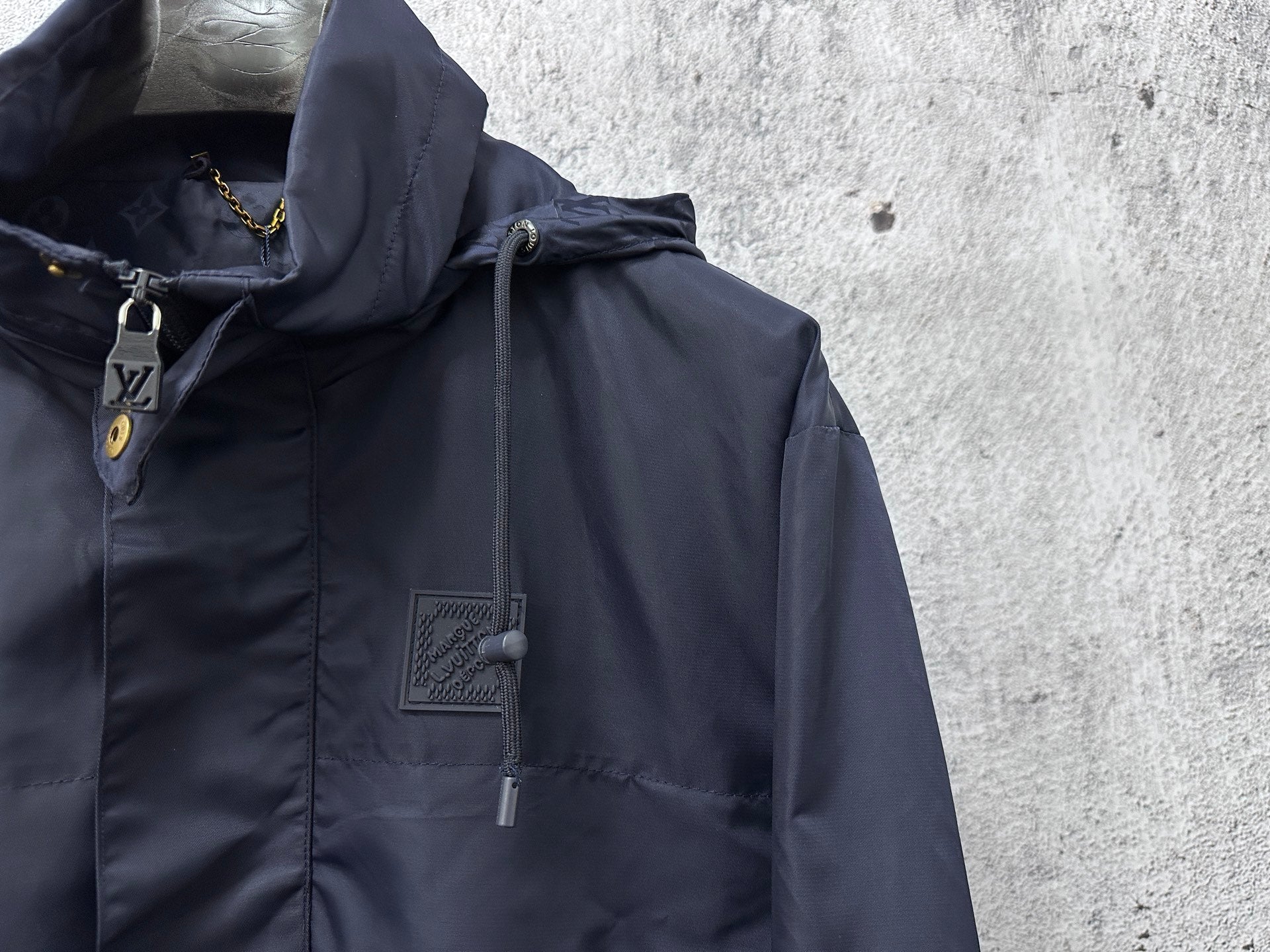 Hooded jacket close-up showing drawstring hood and zipper with dark navy fabric.