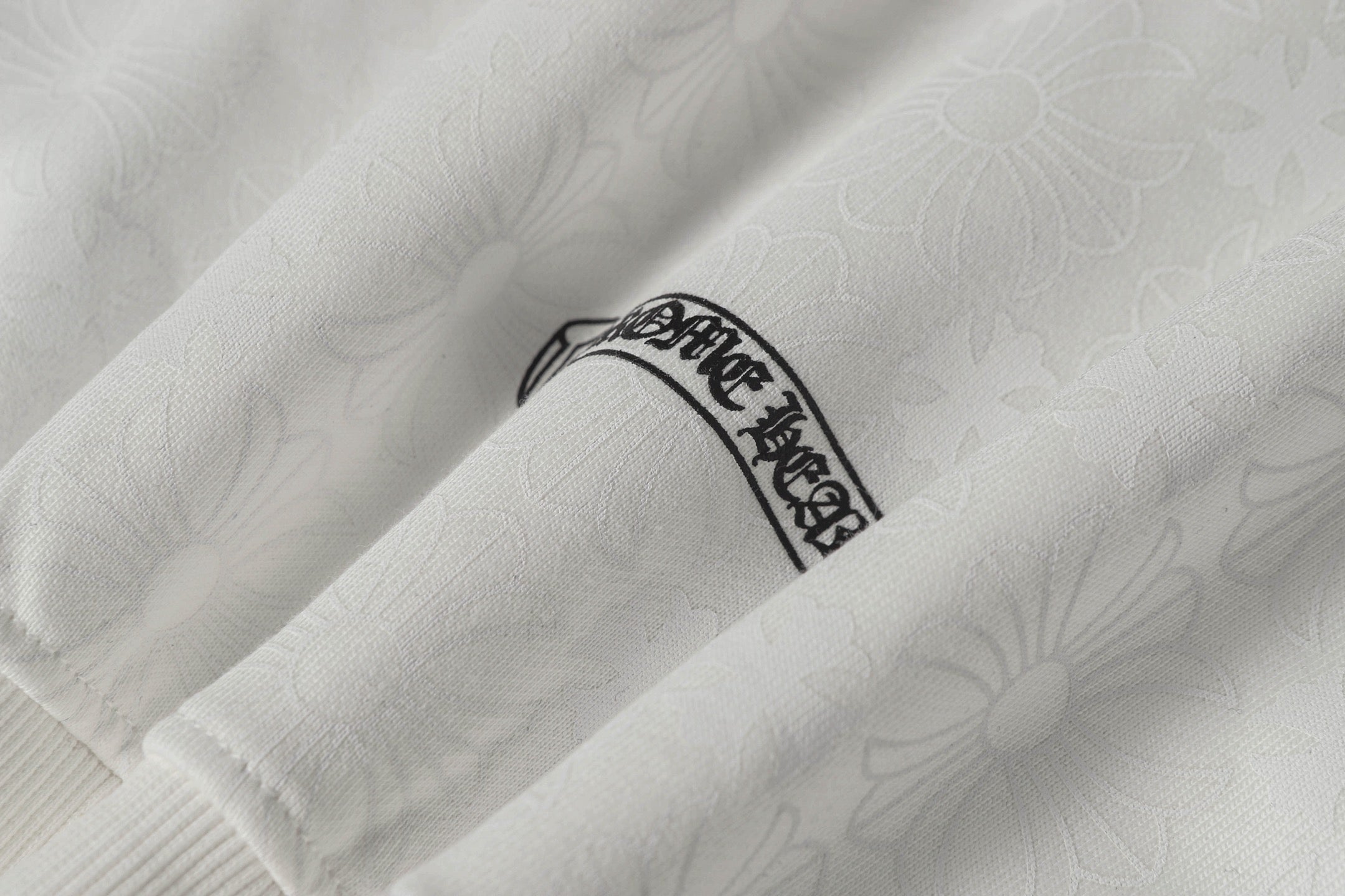 White zip-up hoodie sleeve with small embroidered crest label