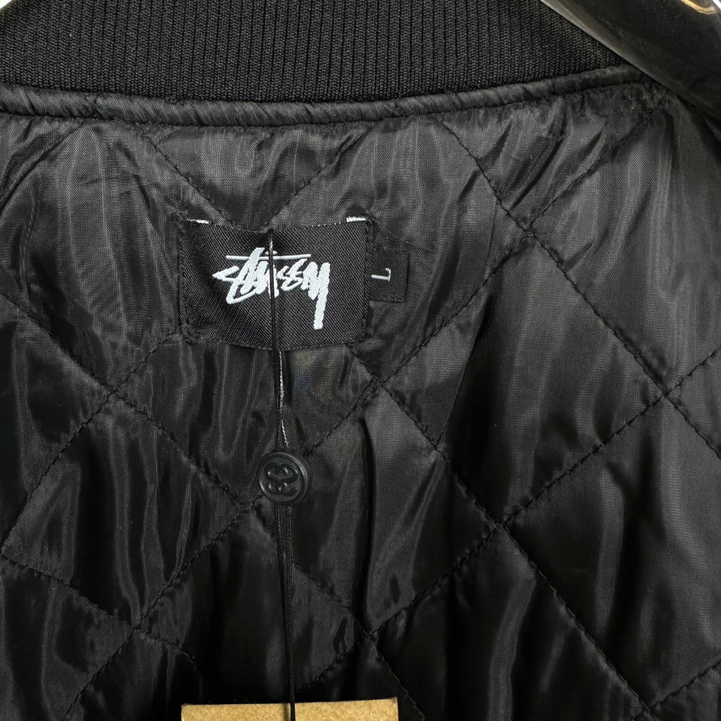 Black quilted bomber jacket interior with Stussy logo label and buttons