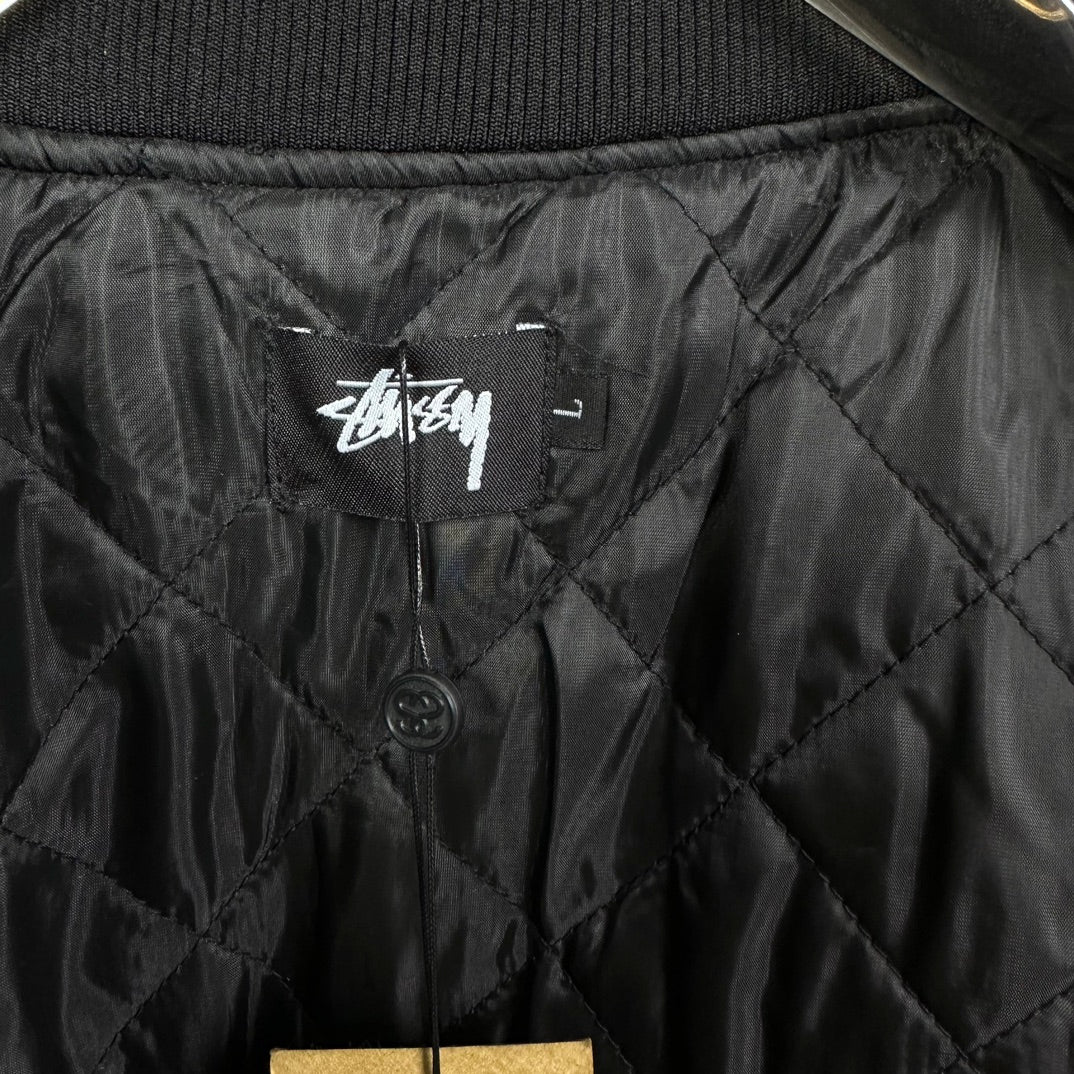 Black quilted bomber jacket interior with Stussy logo label and buttons