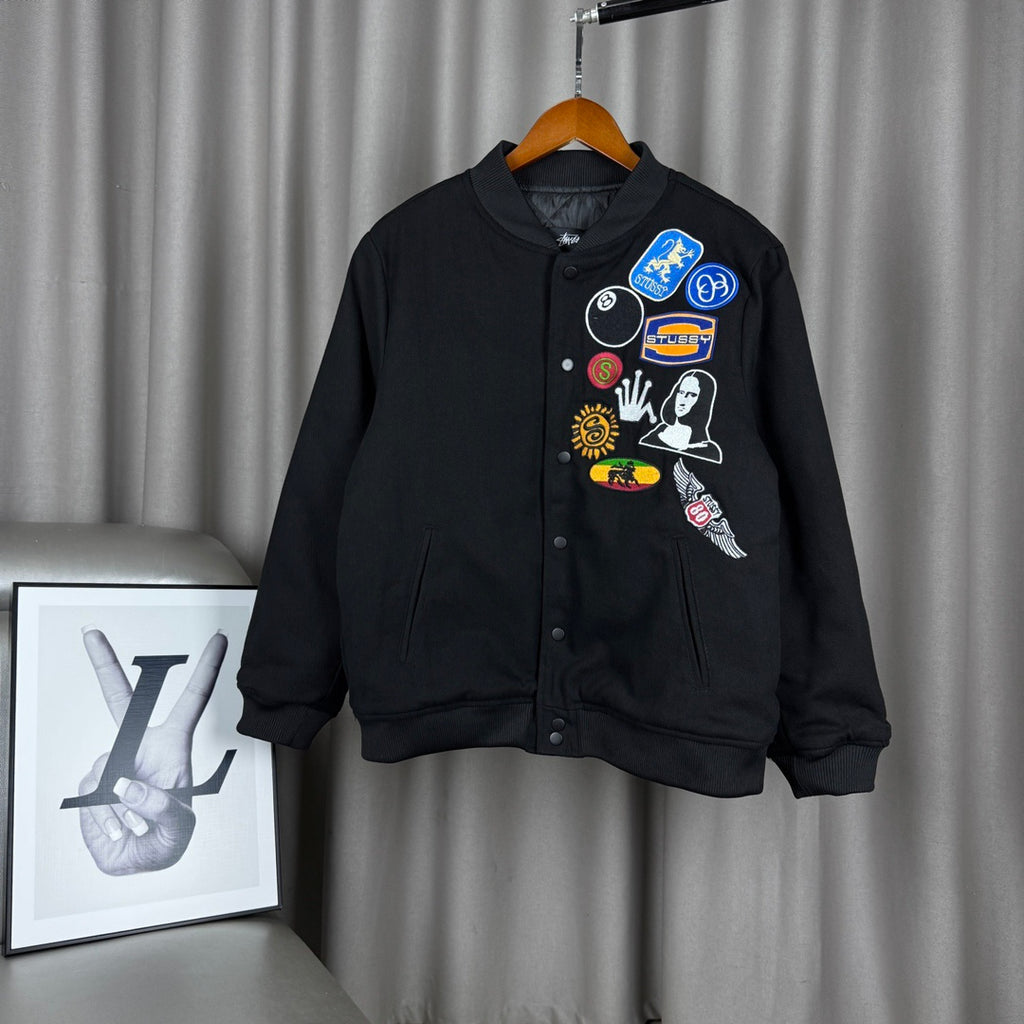 Black bomber jacket with button front and colorful stitched patches on chest
