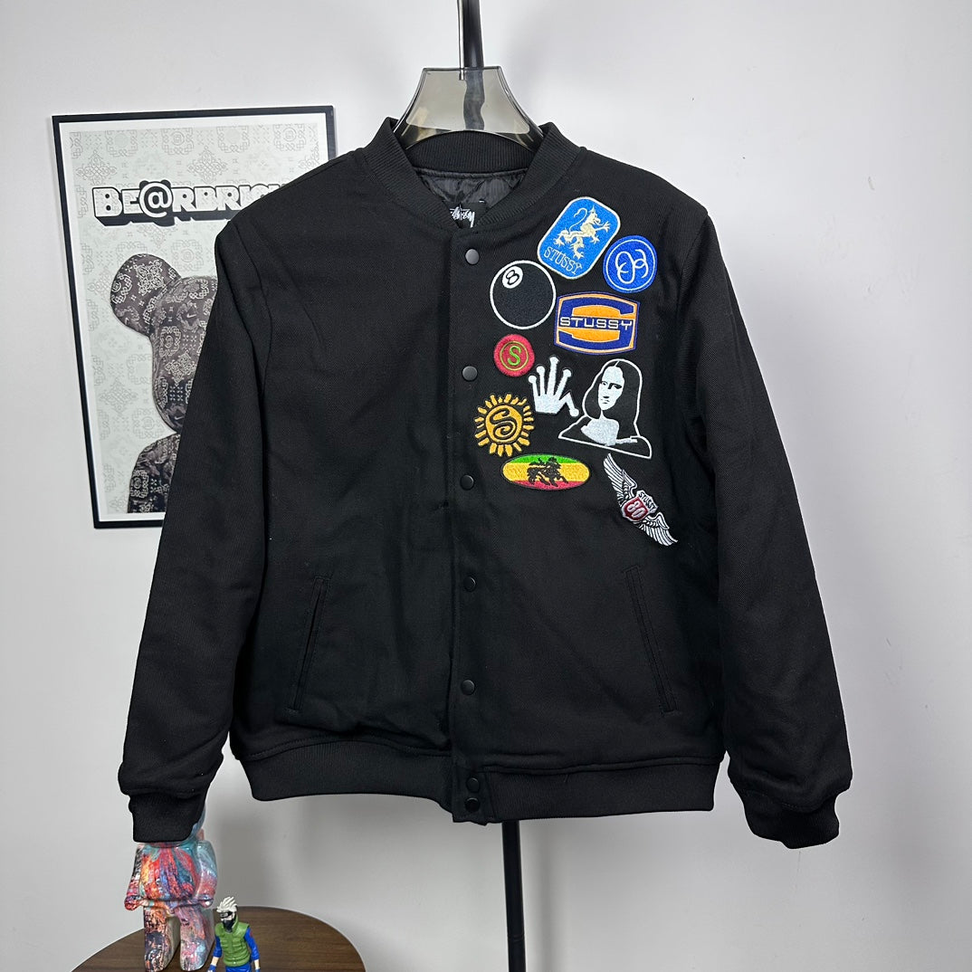 Black Stussy button-front bomber jacket with colorful chest patch graphic