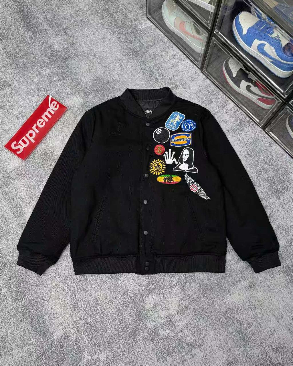 Black button-front jacket with colorful patches on chest and ribbed cuffs