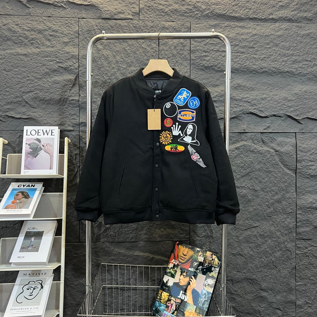 Stussy black bomber jacket, front with colorful patch collage and button placket
