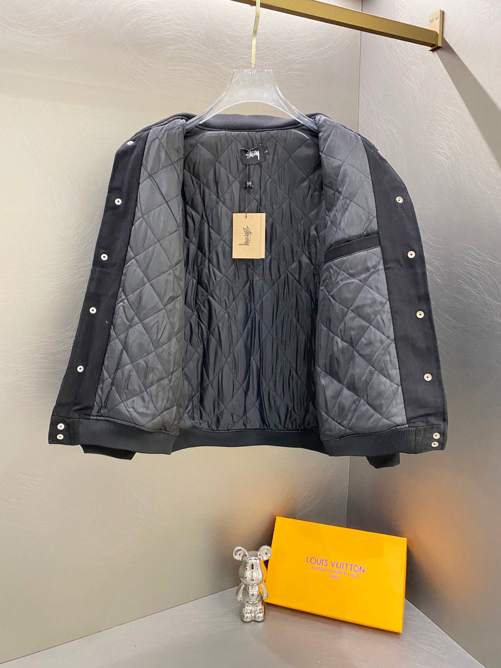 Black quilted snap-front jacket with ribbed cuffs, logo patch at chest