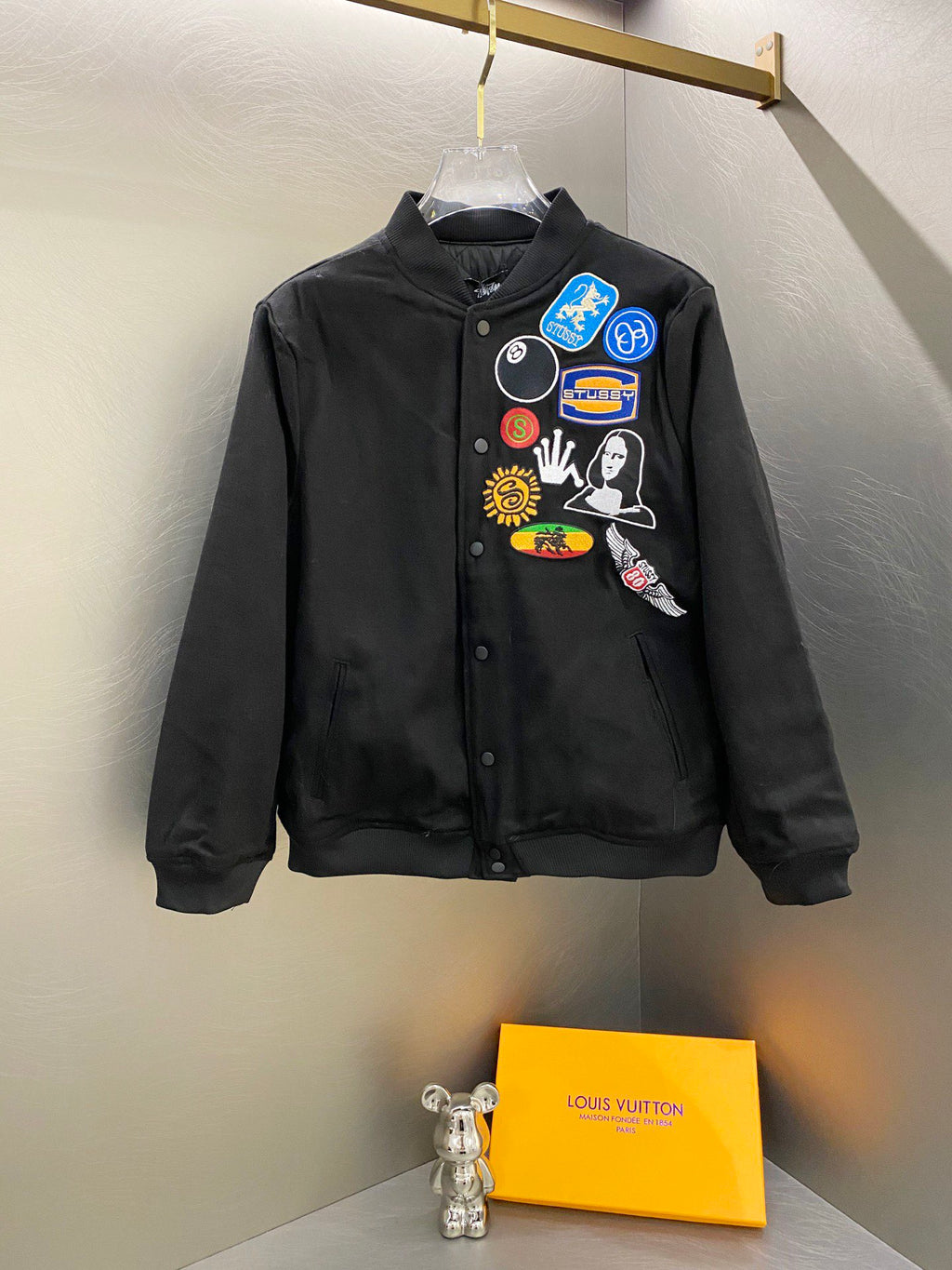 Black Stussy bomber jacket with chest patch graphics and button-front closure