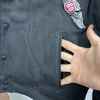 Black bomber jacket sleeve cuff with embroidered patch detail near shoulder