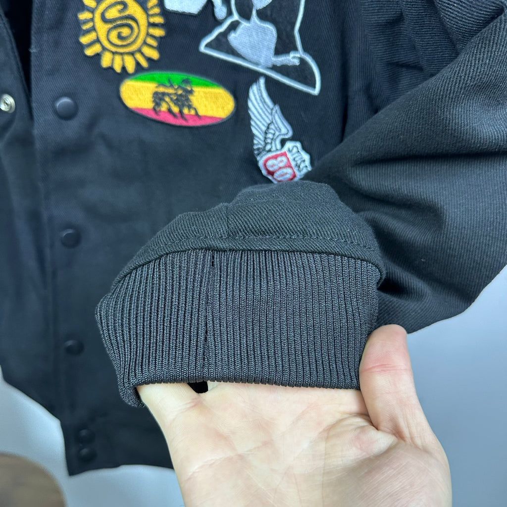 Black bomber jacket ribbed cuff with colorful embroidered patch on sleeve