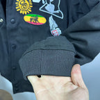 Black bomber jacket ribbed cuff with colorful embroidered patch on sleeve