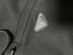Triangular Prada logo patch on dark hoodie fabric