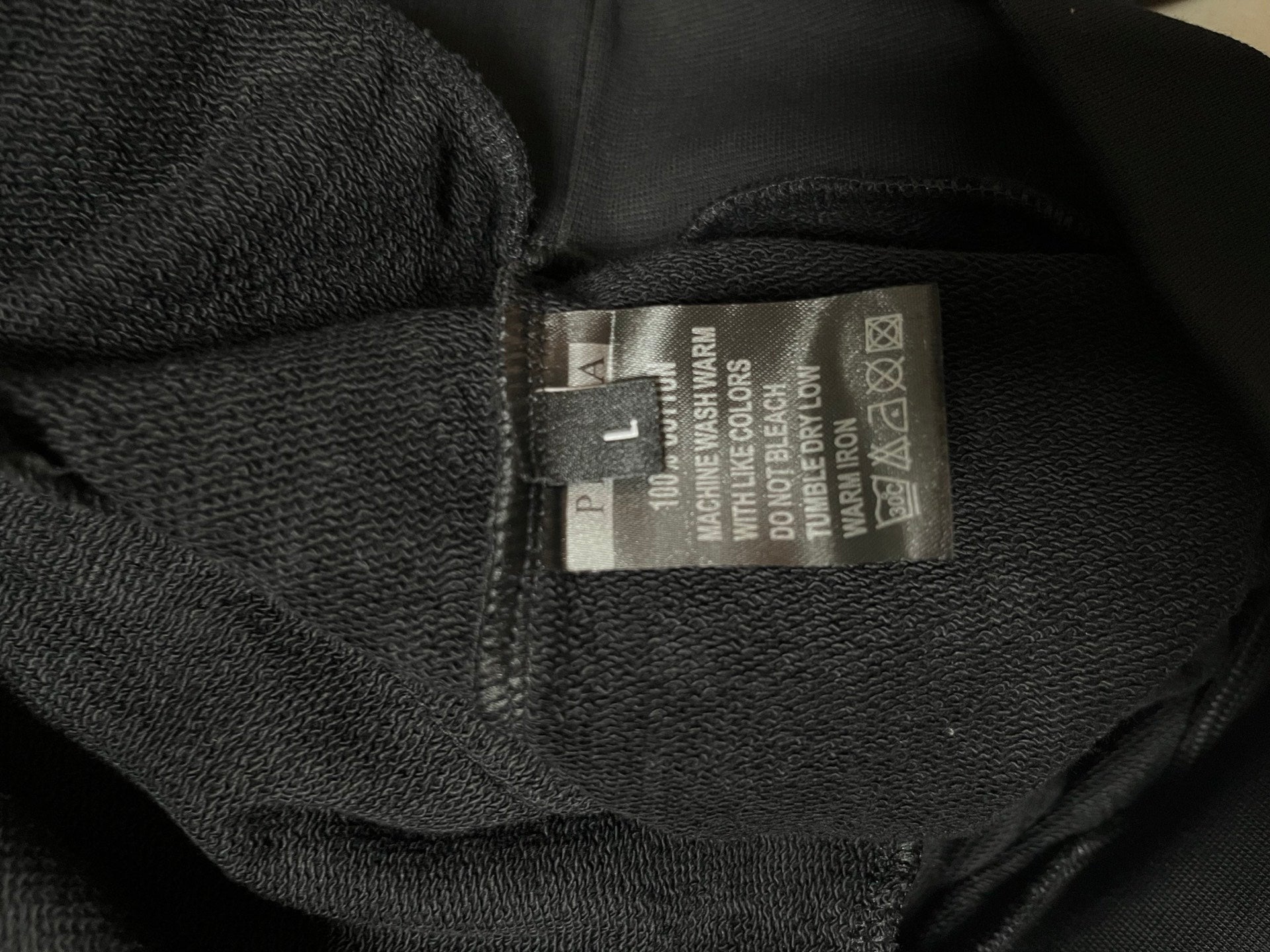 Dark hoodie inner neck label with care and material information