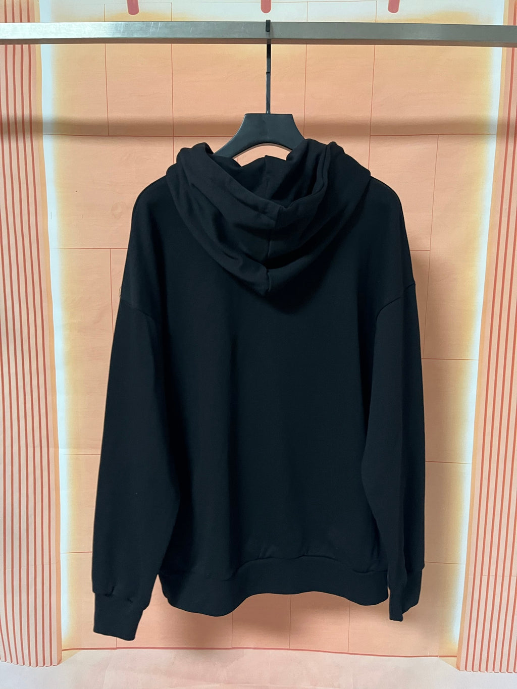 Dark hoodie with hood and front kangaroo pocket, worn on hanger