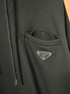 Triangular logo patch on dark hoodie pocket area