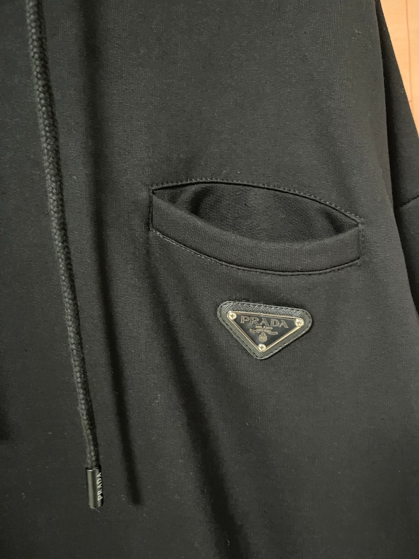 Triangular logo patch on dark hoodie pocket area