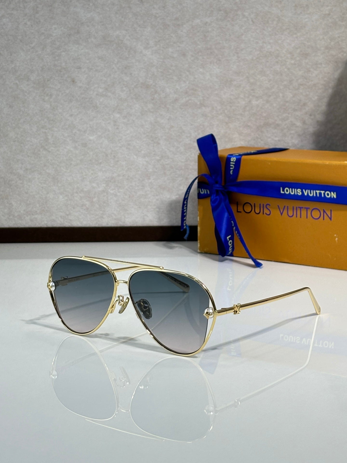 Louis Vuitton sunglasses with dark blue tinted lenses and gold-tone metal frames