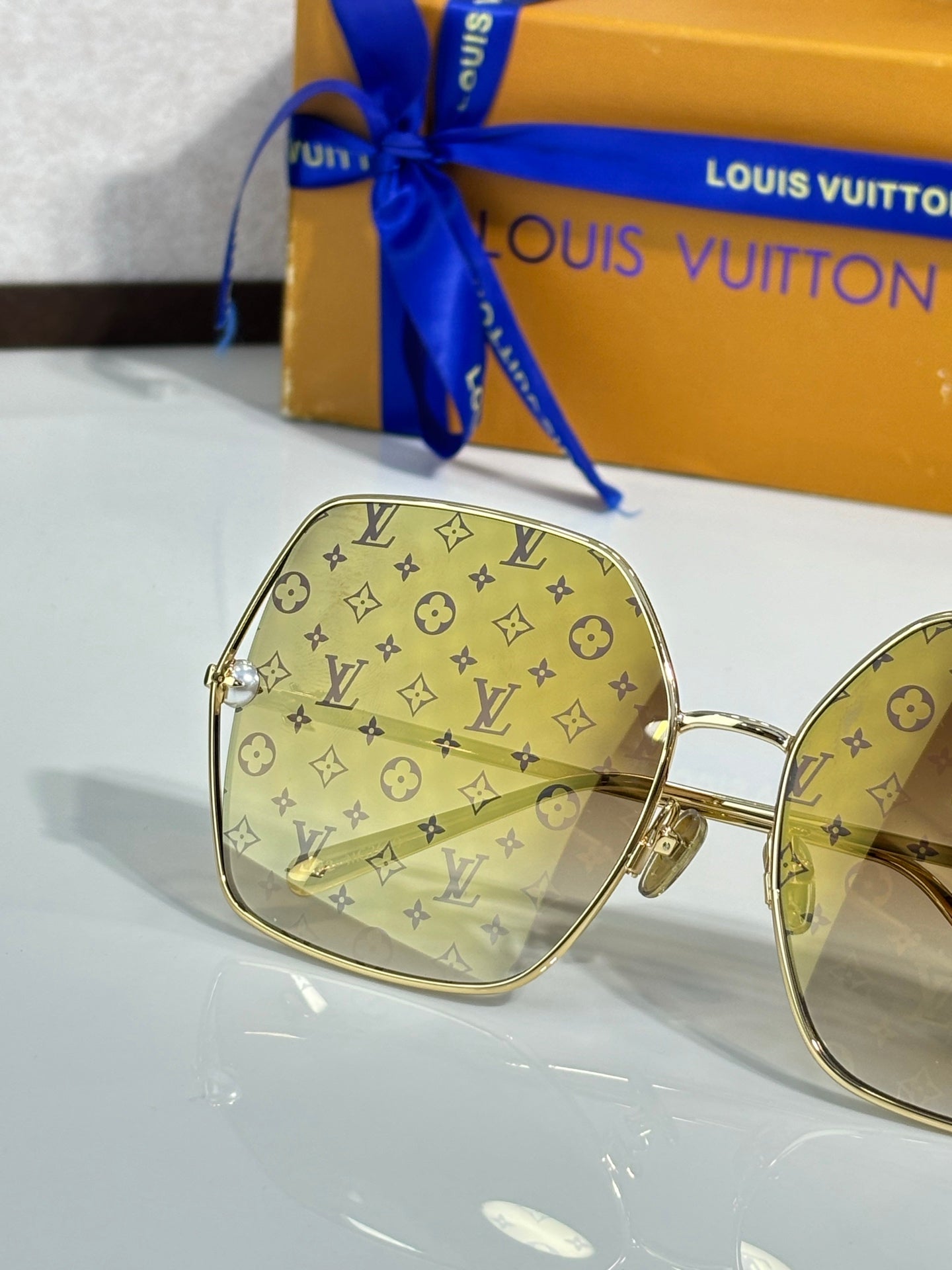 Louis Vuitton sunglasses close-up with tan monogram frames and tinted lenses