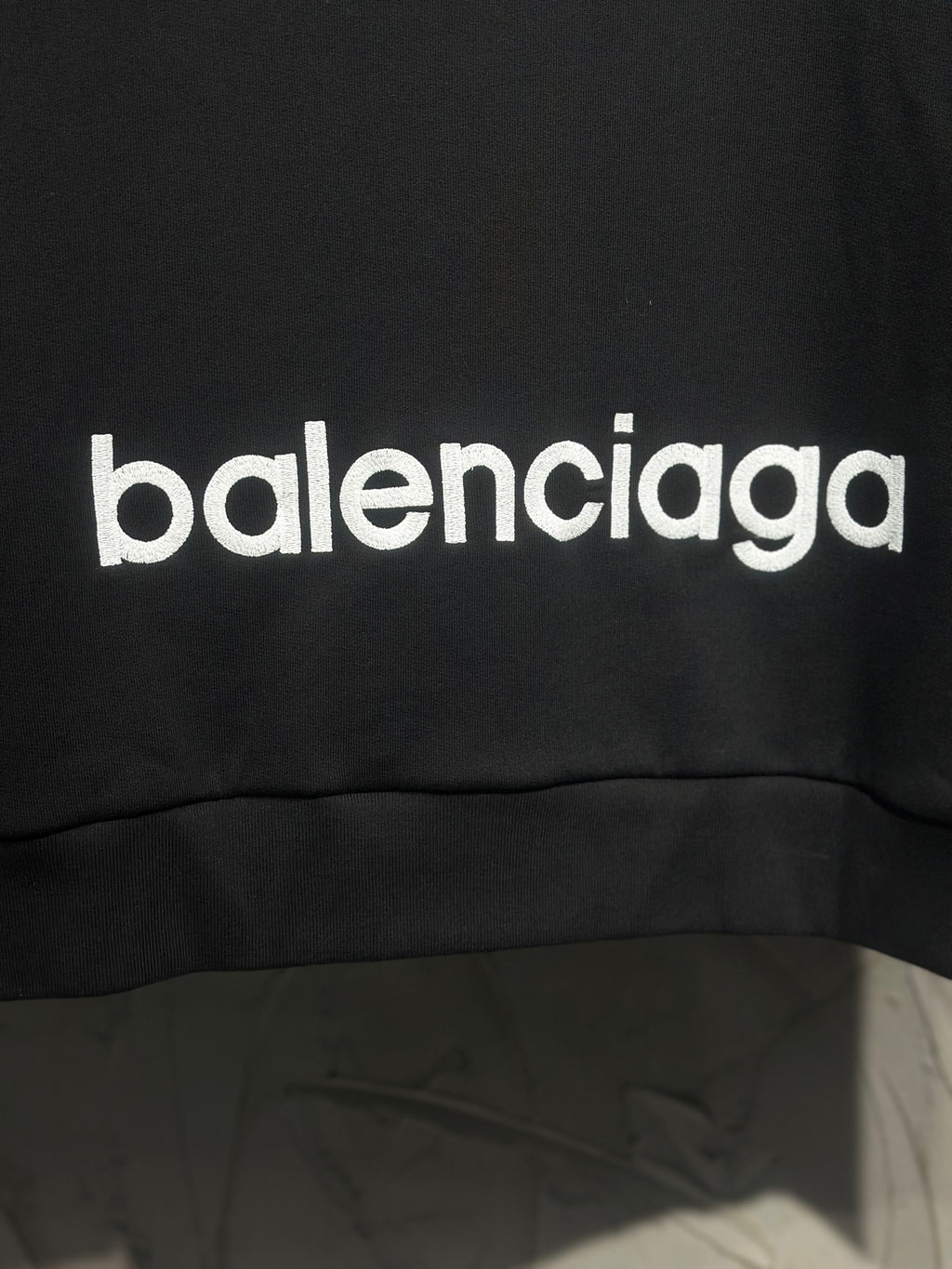 Black hoodie with large white Balenciaga logo print near hem.