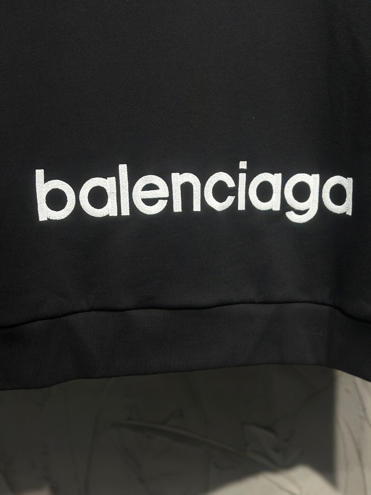 Black hoodie with large white Balenciaga logo print near hem.