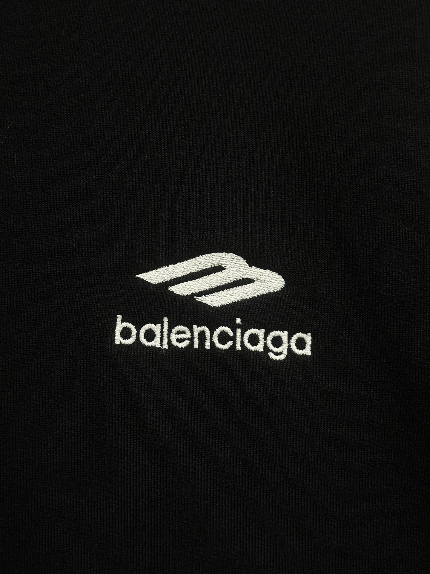 Balenciaga white logo print on black hoodie fabric.
