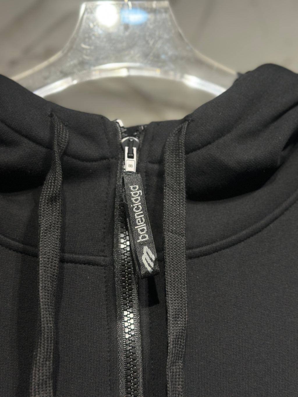 Black hoodie zipper with branded tape and metal zipper pull.