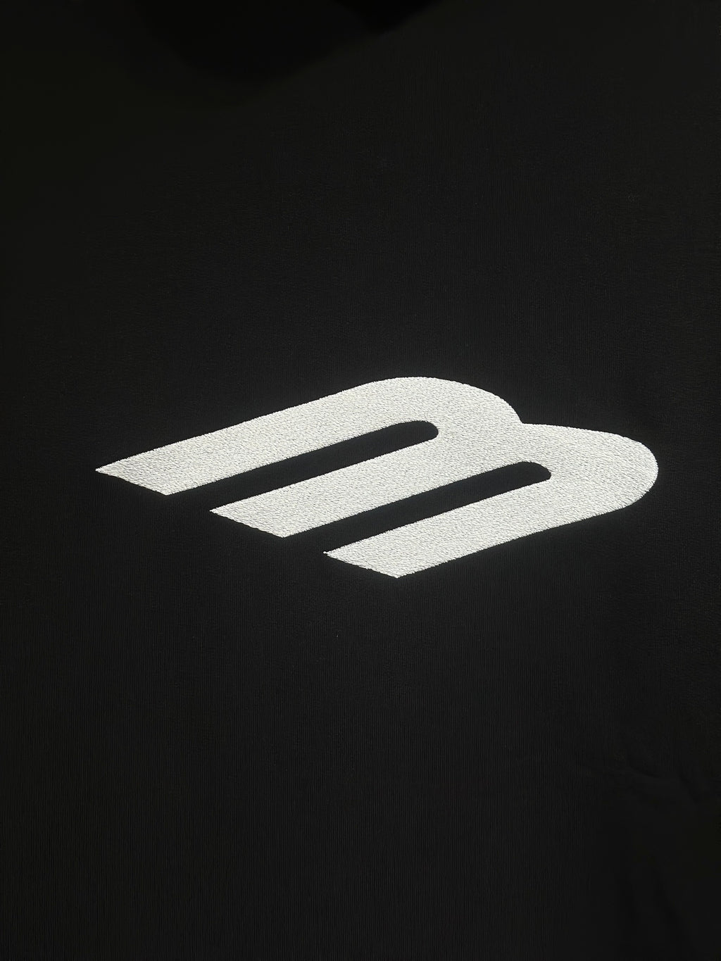 White Balenciaga icon logo on black hoodie fabric.