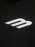 White Balenciaga icon logo on black hoodie fabric.