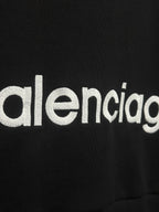 White Balenciaga wordmark on black hoodie fabric.