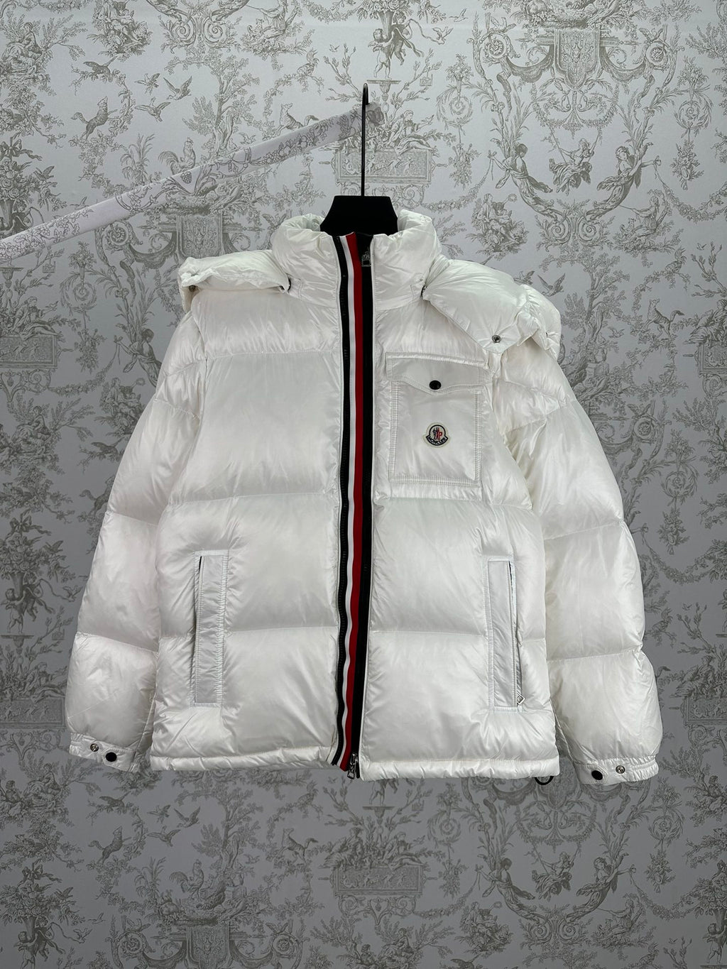 White long puffer jacket with front zip, hood, and red-and-black trim stripe