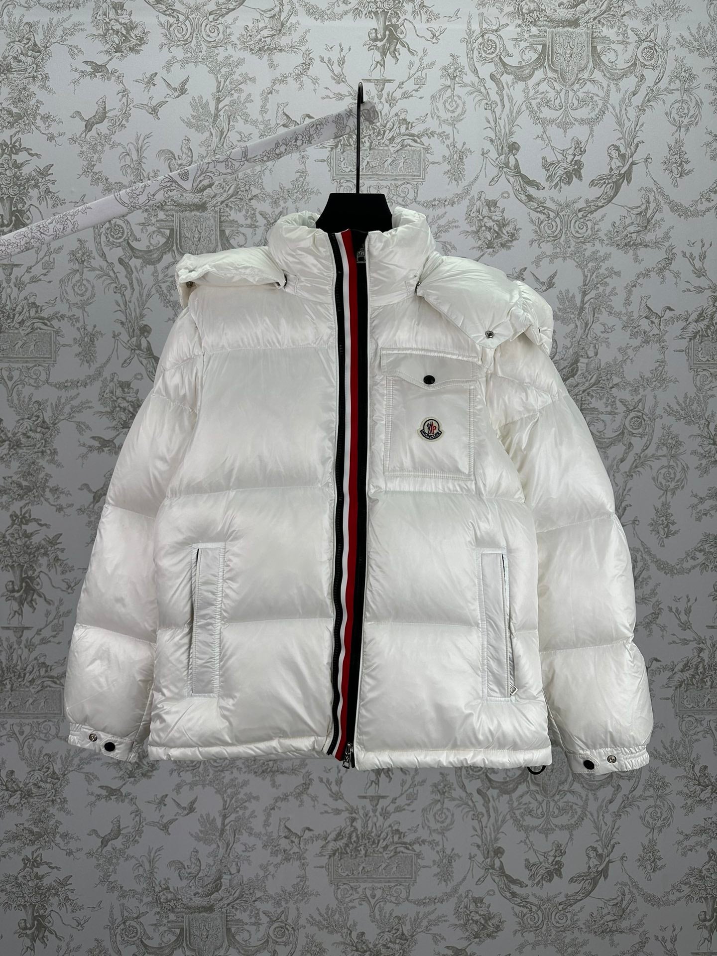 White long puffer jacket with front zip, hood, and red-and-black trim stripe