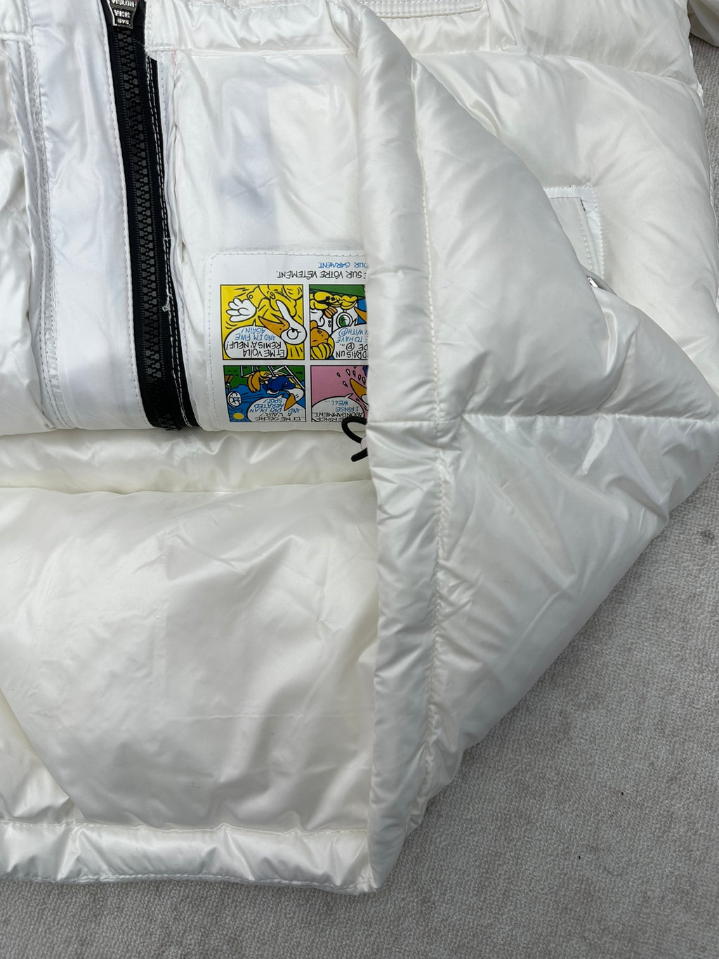 White puffer jacket with interior care label patch and black zip edge