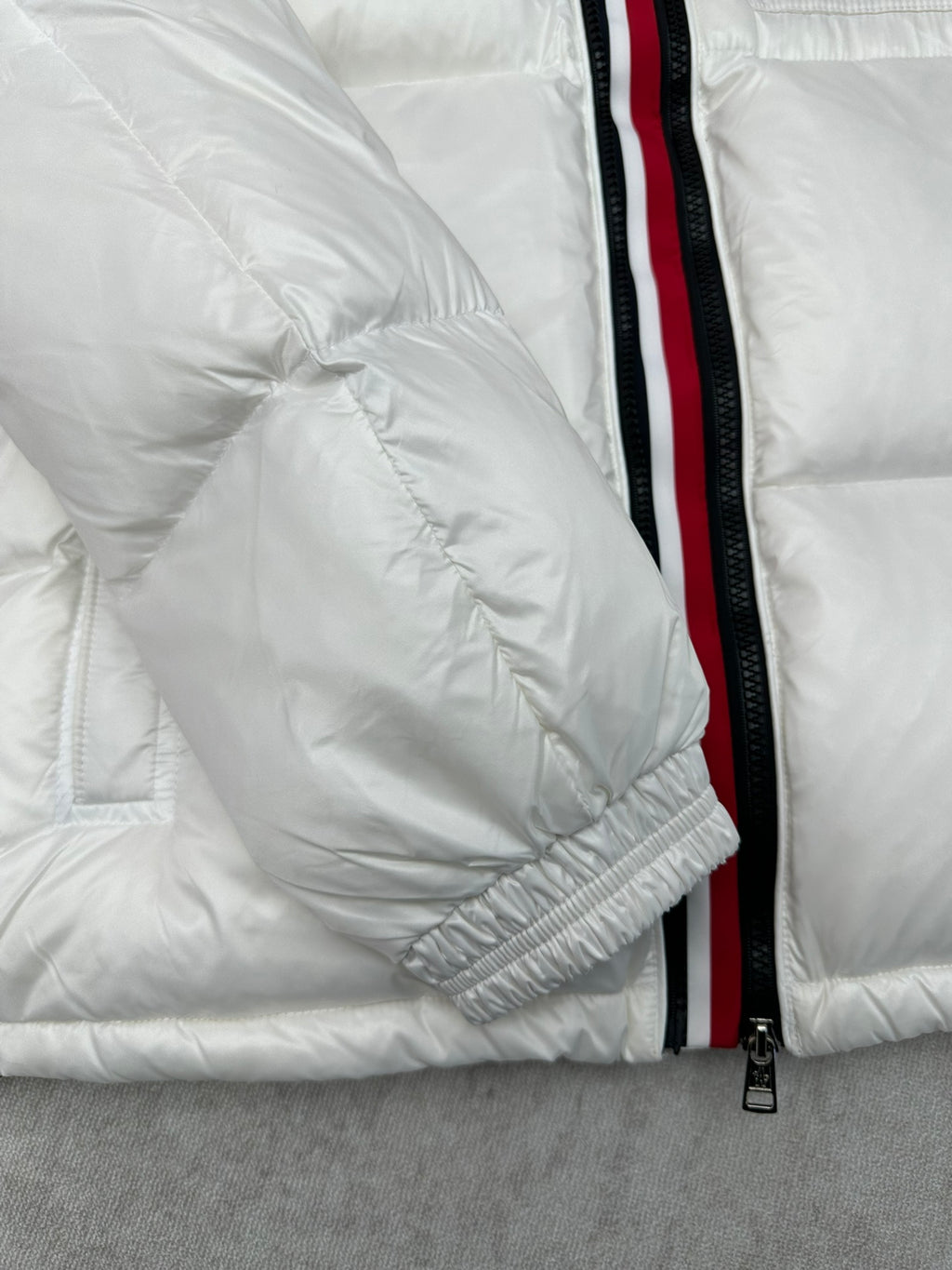 White puffer jacket sleeve with red-trim zipper and elastic cuff