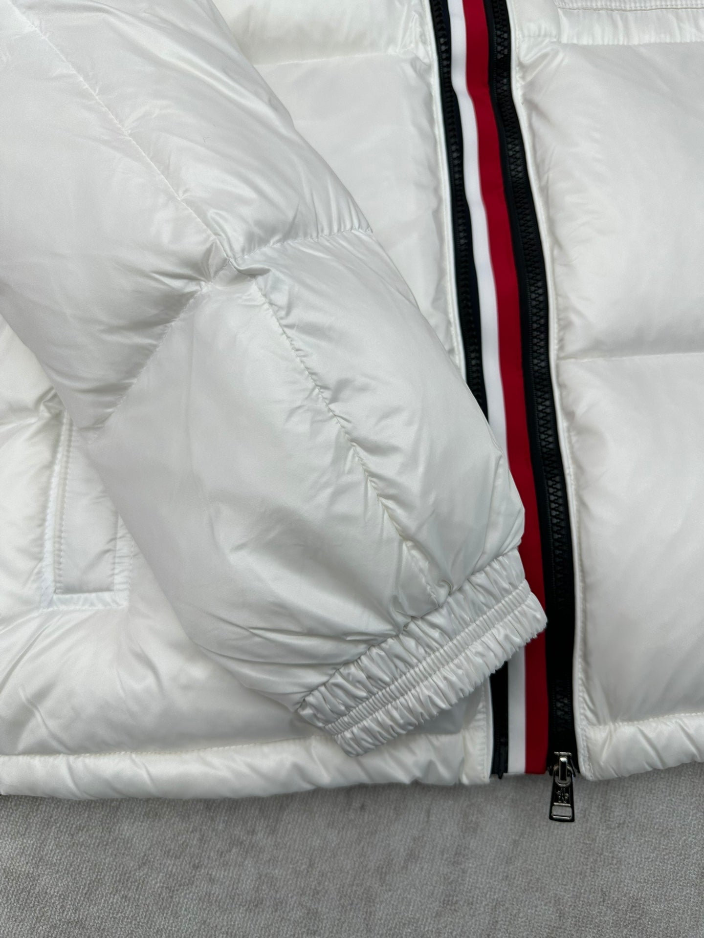 White puffer jacket sleeve with red-trim zipper and elastic cuff