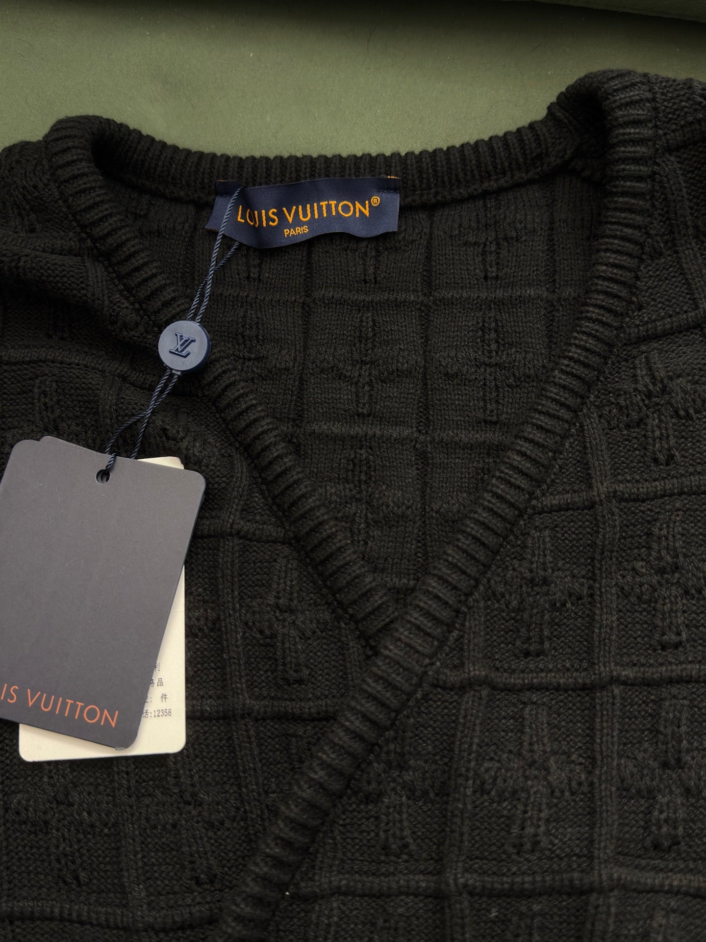 Black knit V-neck top with ribbed collar and Louis Vuitton neck label