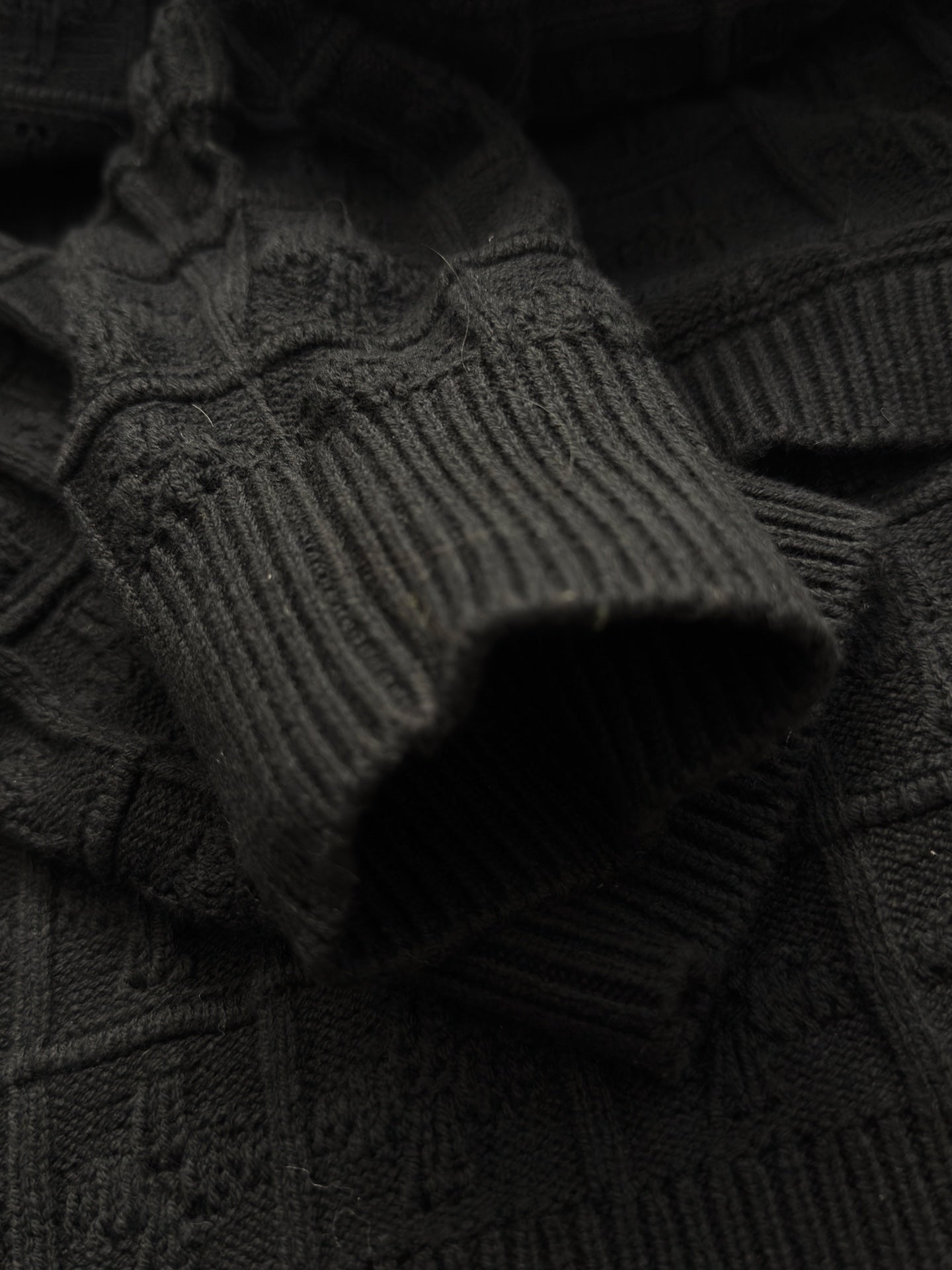 Black knit sleeve with ribbed cuff and textured stitched pattern