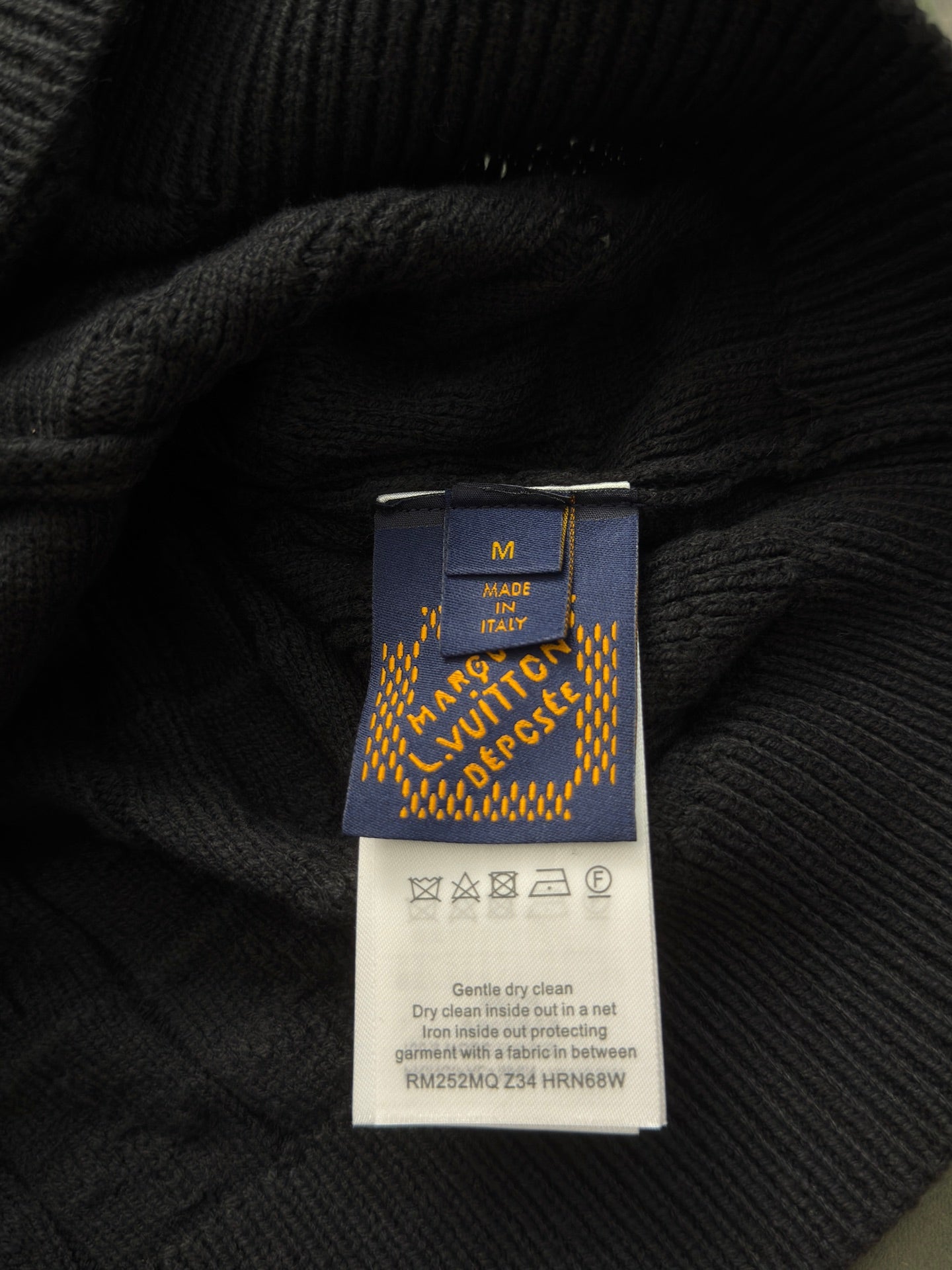 Black knit garment care label with size and cleaning instructions