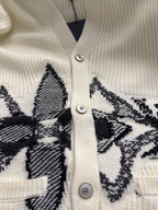 Cream rib-knit cardigan front with silver button placket and black embroidered pattern