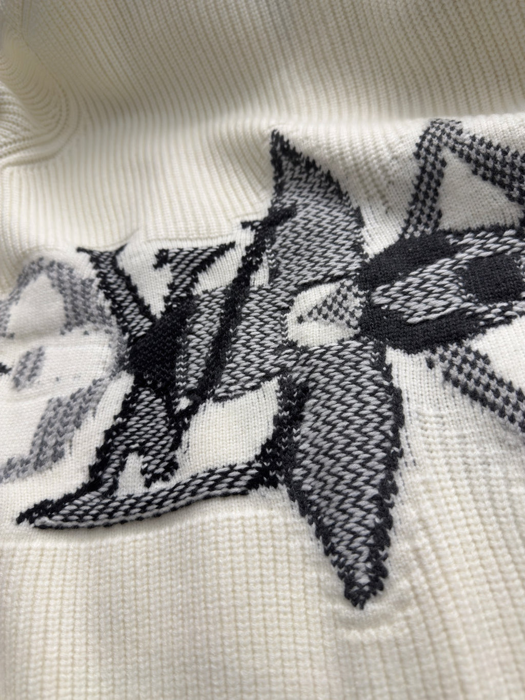 Cream knit cardigan with black starburst embroidery across the front panel