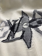 Cream knit cardigan with black starburst embroidery across the front panel