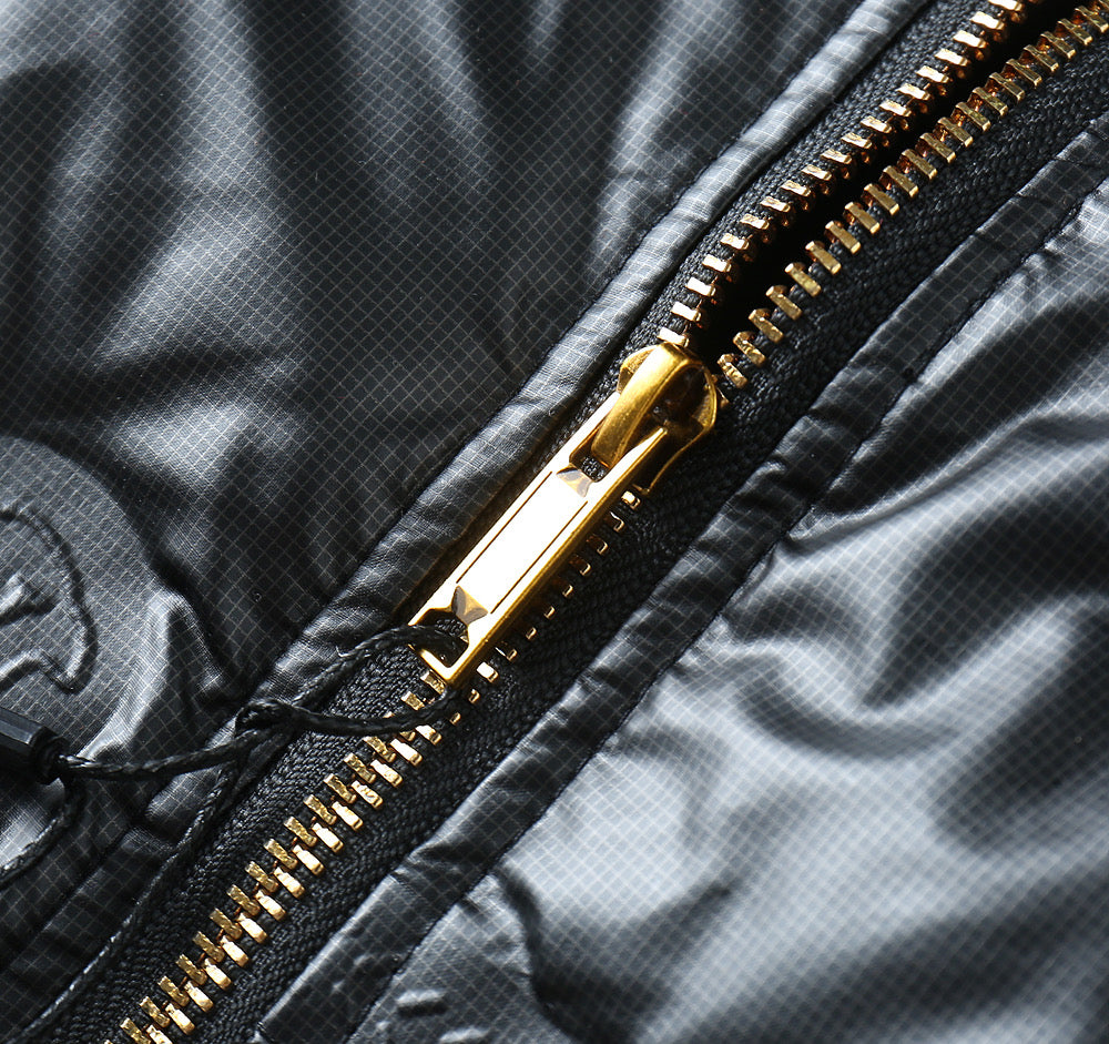 Close-up of gold-tone zipper on glossy quilted jacket fabric
