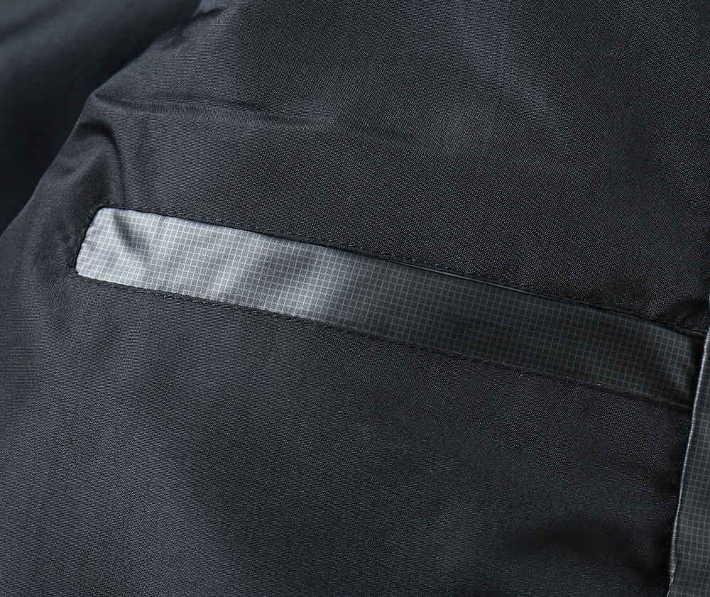 Inner pocket label tab on padded jacket lining, dark fabric with light print