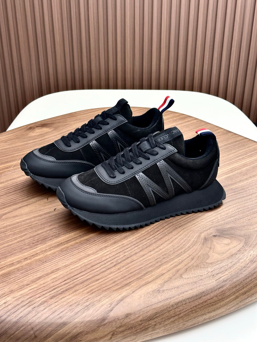 Moncler black sneakers on wooden surface with lace-up and red-white-blue accents