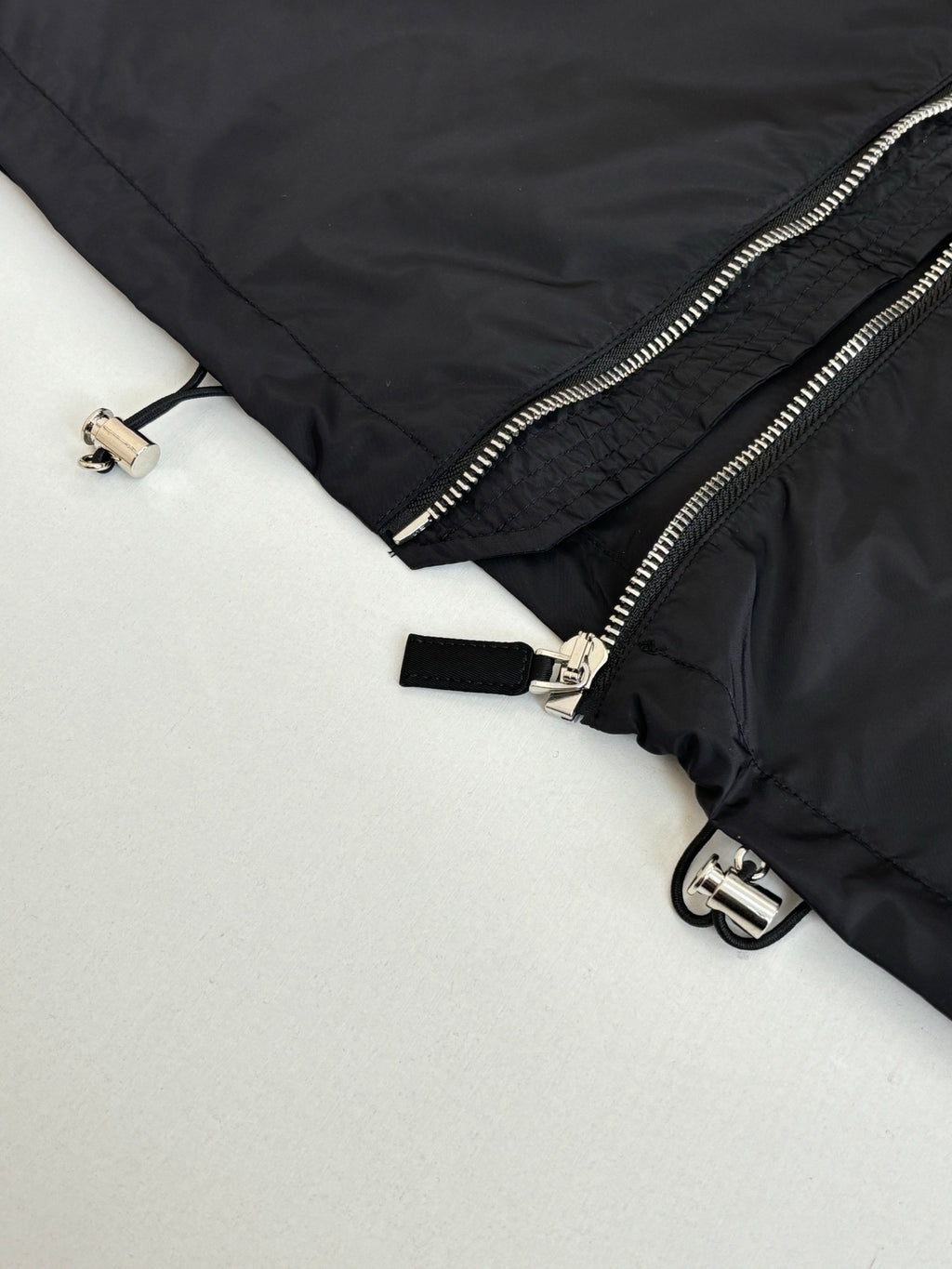 Prada jacket close-up of zipper pull, ring details, and adjustable strap