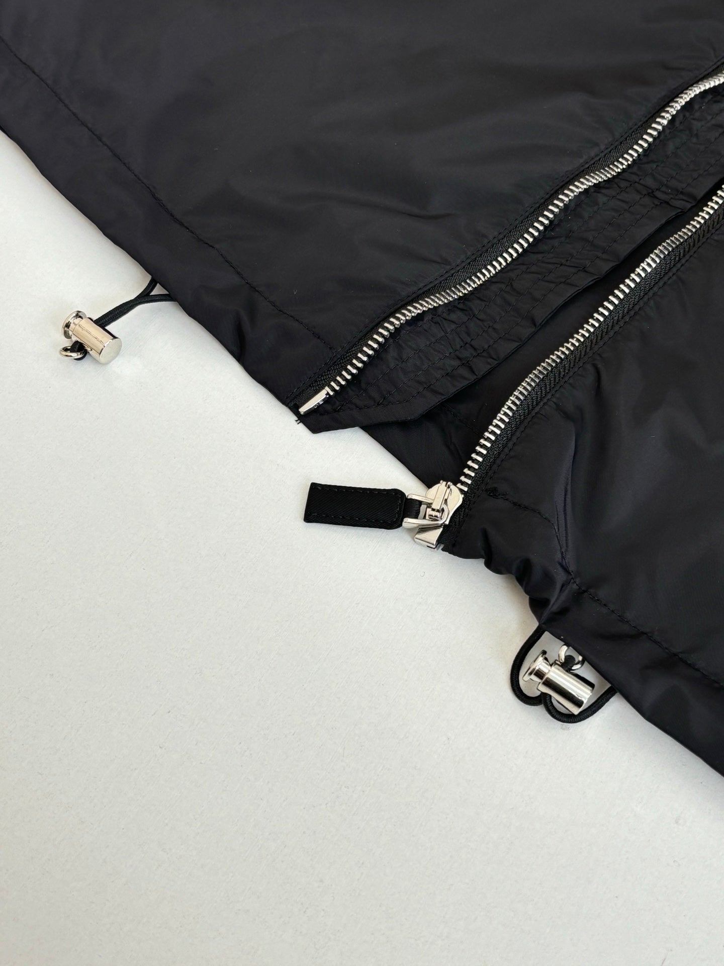 Black puffer jacket side zipper with metal pull and strap tab