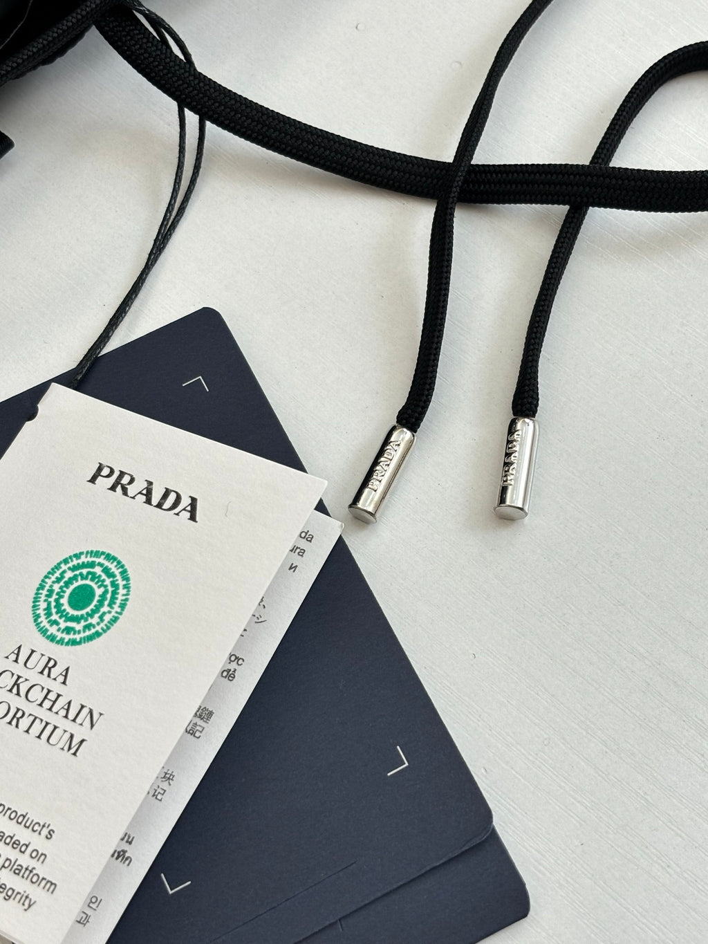 Long garment with drawstring cords, Prada label and blue authenticity tag